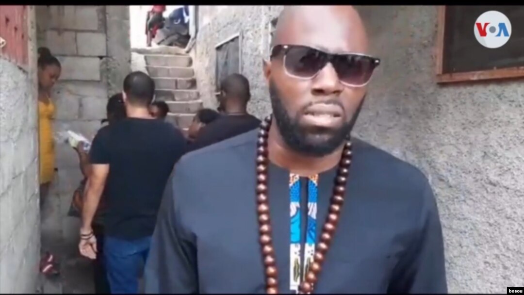 Penulis Benin Perancis, Kémi Seba, membagikan paket sanitas di kawasan-kawasan kumuh di Port au Prince, 16 November 2019. (Foto: W.Bossou/ VOA Creole)