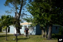 Alexis Llanos, de 27 años, recorta el césped de la casa a la que se mudó la familia Llanos en octubre de 2023, en Lehigh Acres, Florida, el 27 de diciembre de 2023. (Foto AP/Rebecca Blackwell)