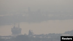 FILE - A cargo ship is seen through air pollution along the Chao Phraya river in Bangkok, Thailand, Jan. 11, 2019. 