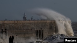 Locals look on as high winds from Storm Bert cause waves to crash over the harbour arm in Folkestone, Britain, Nov. 24, 2024. 