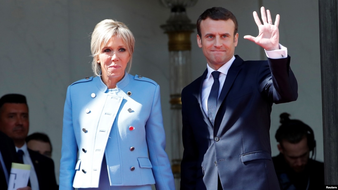 French President Emmanuel Macron and his wife, Brigitte Trogneux, wave to former President Francois Hollande as he leaves after the handover ceremony at the Elysee Palace in Paris, May 14, 2017.