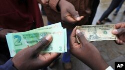 FILE: Zimbabweans comparing the new note with the U.S. dollar note following the introduction of new notes by the Reserve Bank of Zimbabwe in Harare, Nov, 28, 2016. 