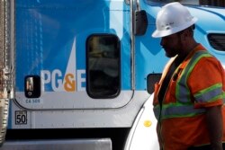 FILE - A Pacific Gas & Electric worker walks in front of a truck in San Francisco, California, Aug. 15, 2019.