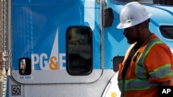 FILE - A Pacific Gas & Electric worker walks in front of a truck in San Francisco, California, Aug. 15, 2019.