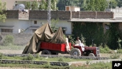 The wreckage of a US helicopter that crashed next to the wall of the bin Laden compound in Abbottabad being transported by Pakistani officials, May 2, 2011