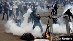 An anti-government protester throws a teargas canister back at police during riots at Altamira square in Caracas, March 6, 2014. 