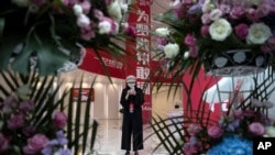 An attendee wearing a mask to curb the spread of the new coronavirus is framed by flowers sent for the ceremony to mark the listing of JD.com on the Hong Kong Stock Exchange at the JD.com headquarters in Beijing on June 18, 2020.
