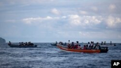 Para wisatawan menaiki perahu dengan harapan bisa melihat paus bungkuk muncul ke permukaan di perairan Bahía Solano, Kolombia.