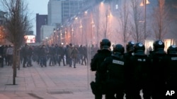 Protesters throw stones toward police in riot gear guarding the government building in Pristina, Kosovo, Jan. 24, 2015.