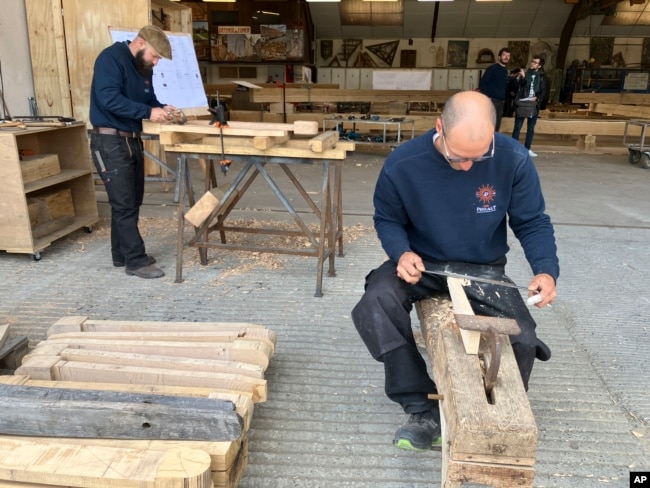 Carpenters work on pieces, part of the new roof for the Notre Dame de Paris cathedral on May, 25, 2023, near Angers, western France. (AP Photo/Jeffrey Schaeffer)