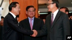 Cambodian Prime Minister Hun Sen, left, shakes hands with opposition party leader Sam Rainsy, right, after a meeting, as Sar Kheng, center, deputy prime minister, looks on at the National Assembly in Phnom Penh, Cambodia, Monday, Sept. 16, 2013.