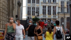 People wear protective face masks as they walk through the Grand Place in the historical center of Brussels, Belgium, Aug. 12, 2020.