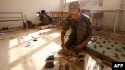 Members of the Kurdish People's Protection Units (YPG) take position in a classroom in the village of Maarouf in the northeastern Syrian province of Hasakeh as they battle Islamic State group jihadists, July 16, 2015.