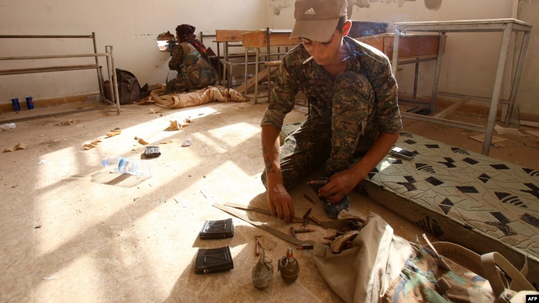 FILE - Members of the Kurdish People's Protection Units (YPG) take position in a classroom in the village of Maarouf in the northeastern Syrian province of Hasakeh as they battle Islamic State group jihadists, July 16, 2015.
