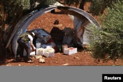 FILE - A Free Syrian Army member inspects goods that were confiscated at a checkpoint during a siege on the Kurdish city of Afrin, in the Aleppo countryside, June 30, 2013.