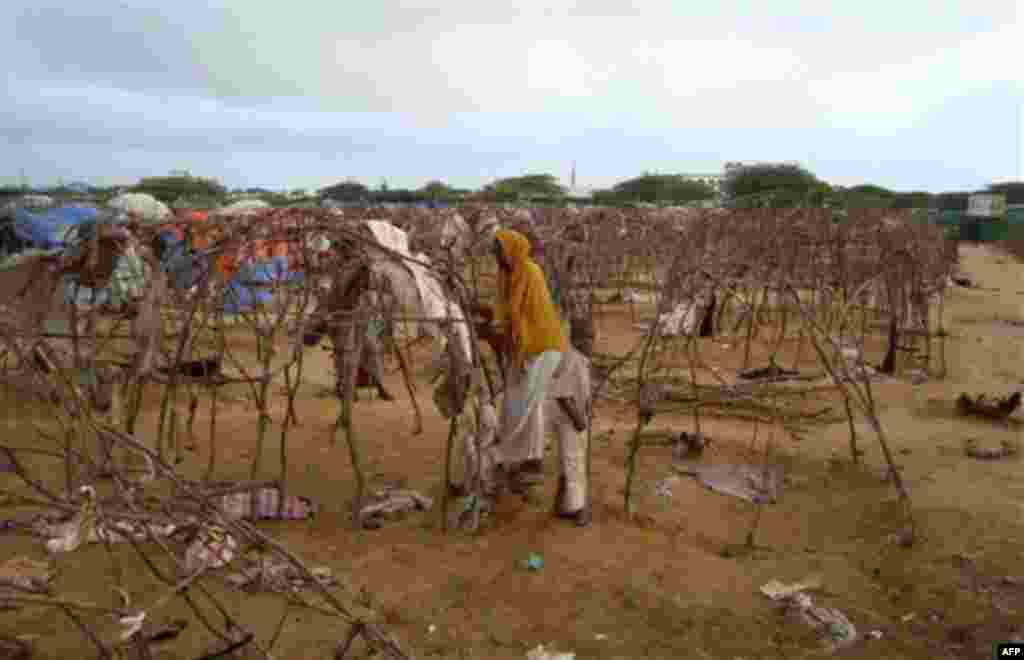 A displaced Somali woman takes her makeshift house apart as she prepares to move from Mogadishu's Badbado camp where a fire fight between Somali government forces and militiamen looting food aid left at least seven people dead Friday Aug. 5, 2011. Somali 