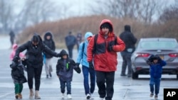 Inmigrantes corren bajo la lluvia hacia las tiendas de campaña en el alojamiento para inmigrantes en Floyd Bennett Field, el martes 9 de enero de 2024, en el distrito de Brooklyn en Nueva York. (Foto AP/Mary Altaffer)