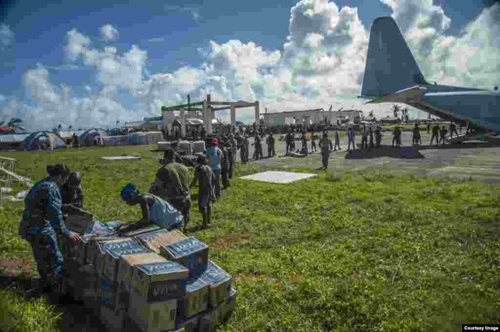 Sailors assigned to the U.S. Navy's forward-deployed aircraft carrier USS George Washington (CVN 73), Marines assigned to the 3 Marine Expeditionary Brigade (3 MEB), and Philippine civilians unload relief supplies in support of Operation Damayan. (US Navy