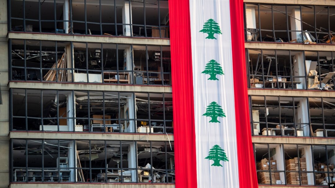 A banner with representations of the Lebanese flag hangs on a damaged building in a neighborhood near the site of last week's explosion that hit the seaport of Beirut, Lebanon, Aug. 12, 2020. 