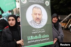 FILE - Women carry a placard of deputy head of Hamas, Saleh al-Arouri, who was killed by what Lebanese and Palestinian security sources say was a drone strike by Israel, at his funeral in Beirut, Lebanon January 4, 2024.