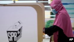 A woman casts her vote during a state election at a voting center in Malacca, Malaysia, Saturday.