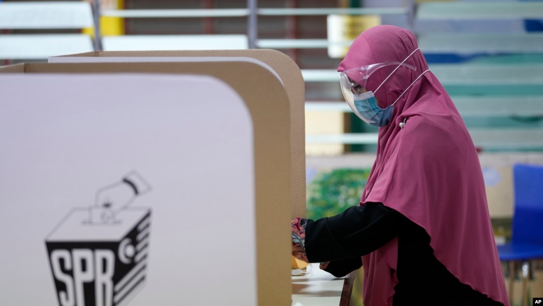 Seorang perempuan memberikan suaranya saat pemilihan negara bagian di sebuah pusat pemungutan suara di Malaka, Malaysia, Sabtu, 20 November 2021. (Foto: AP)