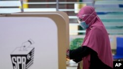 Seorang perempuan melaksananakan hak pilih di sebuah tempat pemungutan suara dalam pilkada di negara bagian Melaka, Sabtu, 20 November 2021. (Foto: AP/Vincent Thian)