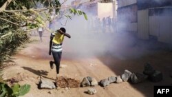 FILE - A Sudanese protester covers his face from tear gas during an anti-government demonstration in the Sudanese capital Khartoum's district of Burri, Feb. 24, 2019.