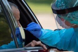 FILE - A health care worker uses a swab to test a man at a coronavirus disease drive-in testing location in Houston, Texas, Aug. 18, 2020.