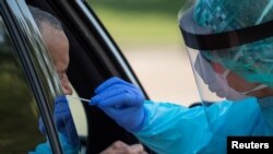 FILE - A health care worker uses a swab to test a man at a coronavirus disease drive-in testing location in Houston, Texas, Aug. 18, 2020. 