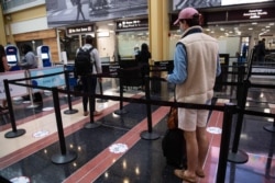 Two people wait in line at a security checkpoint at a virtually deserted Reagan National Airport in Arlington, Virginia, May 22, 2020.