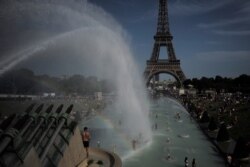 People cool off in the fountains of the Trocadero gardens, in front of the Eiffel Tower, in Paris, Friday, June 28, 2019.