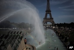 People cool off in the fountains of the Trocadero gardens, in front of the Eiffel Tower, in Paris, Friday, June 28, 2019.