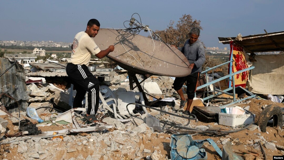 Người Palestine khiêng một vệ tinh ra khỏi đống đổ nát của một căn nhà ở làng Johr El-Deek, Dải Gaza, ngày 17/8/2014.