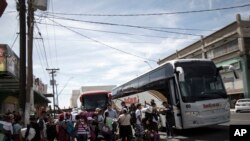 Para 'kafilah' migran pencari suaka Amerika Tengah antri naik bus di Mexicali, Meksiko, yang akan membawa mereka ke Tijuana selama dua jam perjalanan, untuk bergabung dengan sekitar 175 orang lainnya yang sudah tiba, Kamis, 26 April 2018. (Foto AP / Hans-Maximo Musielik)