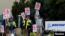 FILE - Boeing factory workers gather on a picket line during the first day of a strike near the entrance of a production facility in Renton, Washington, Sept. 13, 2024.