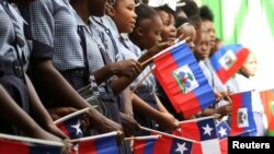 Timoun ann Ayiti ki ap sekwe drapo ayisyen ak drapo chilyen pandan vizit prezidan chilyen alepòk la, Michelle Bachelet tap vizite lekòl Chili finanse ki re Republique du Chili ann Ayiti. REUTERS/Jeanty Junior Agustin - RC1F5E33EFD0