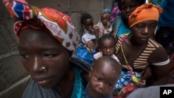 Des femmes déplacées avec leurs enfants attendent de l'aide dans un bâtiment utilisé par des réfugiés comme abri à Pemba, au Mozambique, après avoir fui les attaques à Palma dans le nord du Mozambique, le 19 avril 2021. 