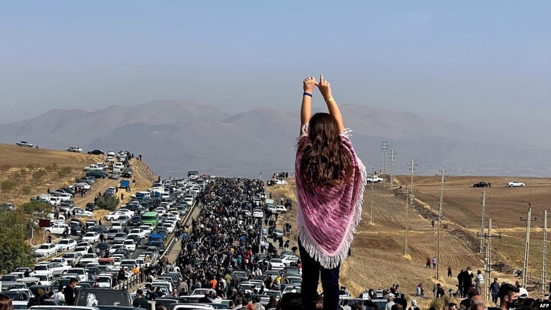 Seorang perempuan tanpa hijab berdiri di atas mobil, sementara massa yang melakukan unjuk rasa bergerak menuju ke kota kelahiran Mahsa Amini di provinsi Kurdistan, Iran barat (foto: ilustrasi). 