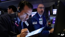 Trader Gregory Rowe, left, and specialist Peter Giacchi work on the floor of the New York Stock Exchange, Thursday, March 12, 2020. 