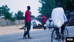 Un cycliste passe devant des éléments de la Force mixte civile qui patrouillent dans les rues à la recherche de combattants de Boko Haram à Maiduguri, au Nigeria, en juin 2016.