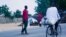 Un cycliste passe devant des éléments de la Force mixte civile qui patrouillent dans les rues à la recherche de combattants de Boko Haram à Maiduguri, au Nigeria, en juin 2016.