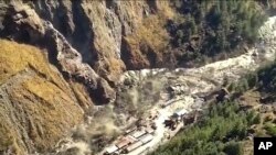 This image take from video provided by KK Productions shows a massive flood of water, mud and debris flowing after part of Nanda Devi glacier broke off, Sunday, Feb.7, 2021. (KK Productions via AP)