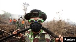 Tentara Indonesia menggunakan kacamata renang untuk melindungi matanya dari asap saat membantu memadamkan kebakaran hutan di desa Parit Indah, Kampar, Riau (8/9). (Reuters/YT Haryono)