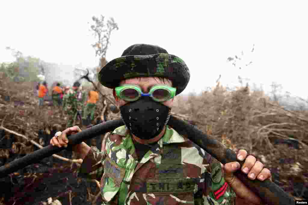 An Indonesian soldier uses swimming goggles to protect his eyes from smoke while helping to fight a fire in a peatland forest area in Parit Indah Village, Kampar, Riau province, Indonesia.