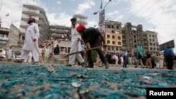 Rescue workers collect shattered glass from the site of a bomb blast on University Road in Peshawar, April 29, 2013.