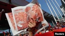 A Pro-China supporter holds up copies of the China Daily while others wave China's national flags at Harbour City, during China's National Day in Hong Kong, China, Oct. 1, 2019.
