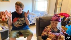 Karen Colby listens on July 22, 2021 in Portland, Ore., while her neighbor Joel Aslin tells how he called an ambulance for her when she got heat stroke as temperatures reached 107 F in her small fifth-floor studio apartment.