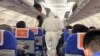 Health workers in protective suits check the condition of a passenger on an airplane that had just landed from Changsha, a city in a province neighboring the center of the coronavirus outbreak, Hubei province, in Shanghai, China Jan. 25, 2020.