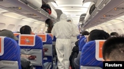 FILE - Health workers in protective suits check the condition of a passenger on an airplane that just landed from Changsha, a city in a province neighboring the center of coronavirus outbreak Hubei province, in Shanghai, Jan. 25, 2020. 